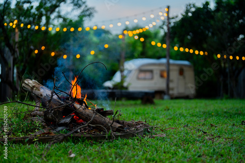 Cozy Night Campfire by Vintage Trailer with String Lights in Garden