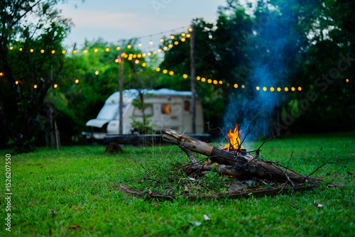 Cozy Night Campfire by Vintage Trailer with String Lights in Garden