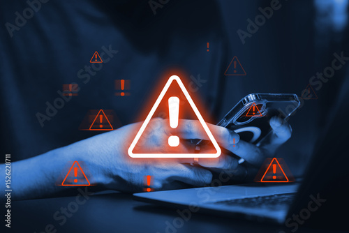 Bild auf Leinwand Digital cybersecurity alert with glowing orange warning signs overlaying a person's hands holding a smartphone and laptop in a dark, tech-focused environment
