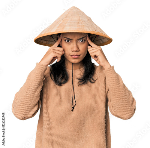 Young Filipina with Vietnamese hat focused on a task, keeping forefingers pointing head.
