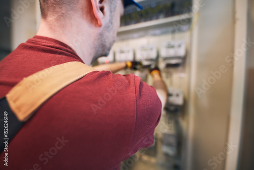 Electrician working on a modern electricity power meter station in a building.