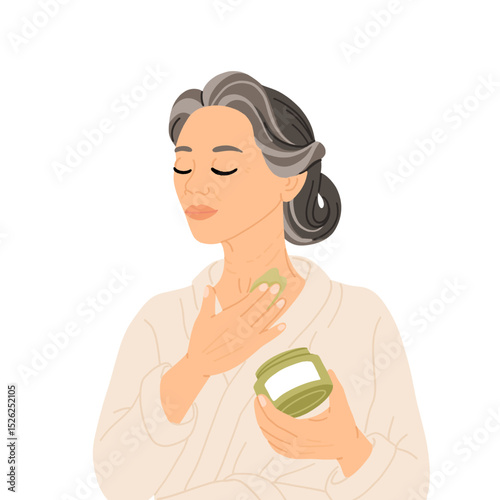 Middle aged East Asian woman with braided gray hair in white bathrobe applying night cream to neck as part of skincare routine. Evening self care for mature skin and graceful aging.