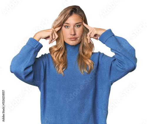 Caucasian blonde woman in studio focused on a task, keeping forefingers pointing head.