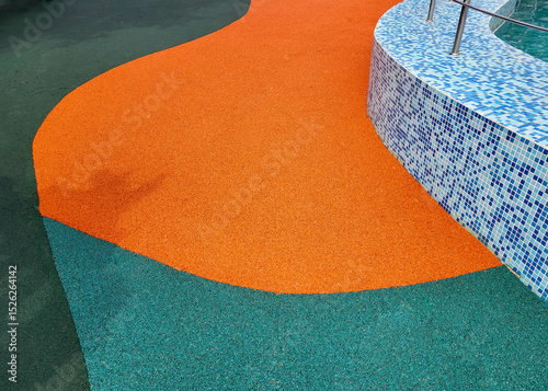 A small blue tile on the pool wall and a colorful rubber coating on the outdoor floor