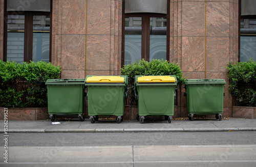 green recycling containers with yellow lids on city street, concept of urban waste segregation