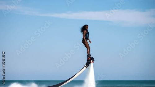 Woman performing flyboarding water sport activity over ocean on a sunny day footage