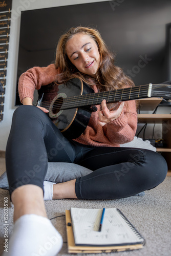 Teenage girl learning to play guitar at home. Girl composing music. Guitar.