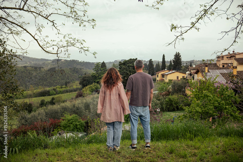 Couple in love admiring the view of Tuscan nature. Beautiful landscape of Italian Tuscany, woman and man standing with their backs to the camera admiring the scenery