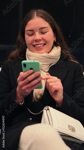 A happy female passenger immersed in her smartphone, exploring various applications and browsing the internet while riding the subway, showcasing the joy of technology during her daily travel routine