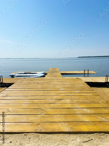 Wooden dock stretches into calm summer lake with inflatable boat