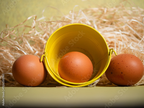 Free range eggs and hay on yellow background 