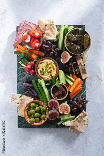 A colorful mezze platter with fresh speads, dips, vegetables and olives