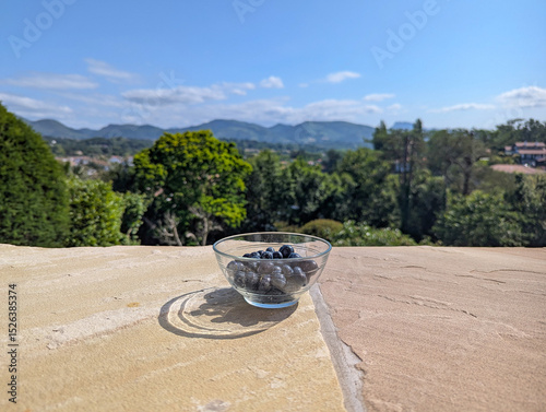 Mirtilos numa taça de vidro com vista panorâmica para as montanhas. Fruta fresca e o esplendor da natureza ao fundo photo