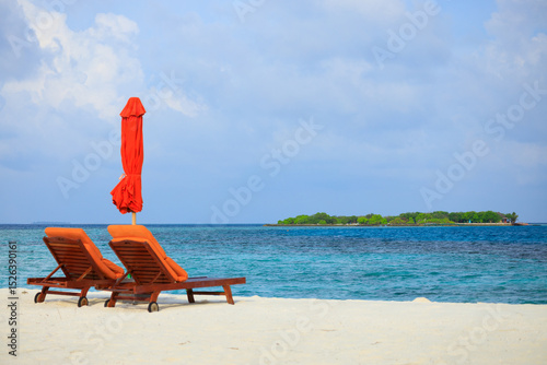 Fototapeta Naklejka Na Ścianę i Meble -  Two sunbeds on a scenic beach of a luxury private island resort in the Maldives
