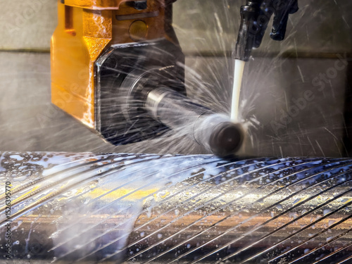 Metal cutting process in a workshop with water coolant spraying on a rotating shaft