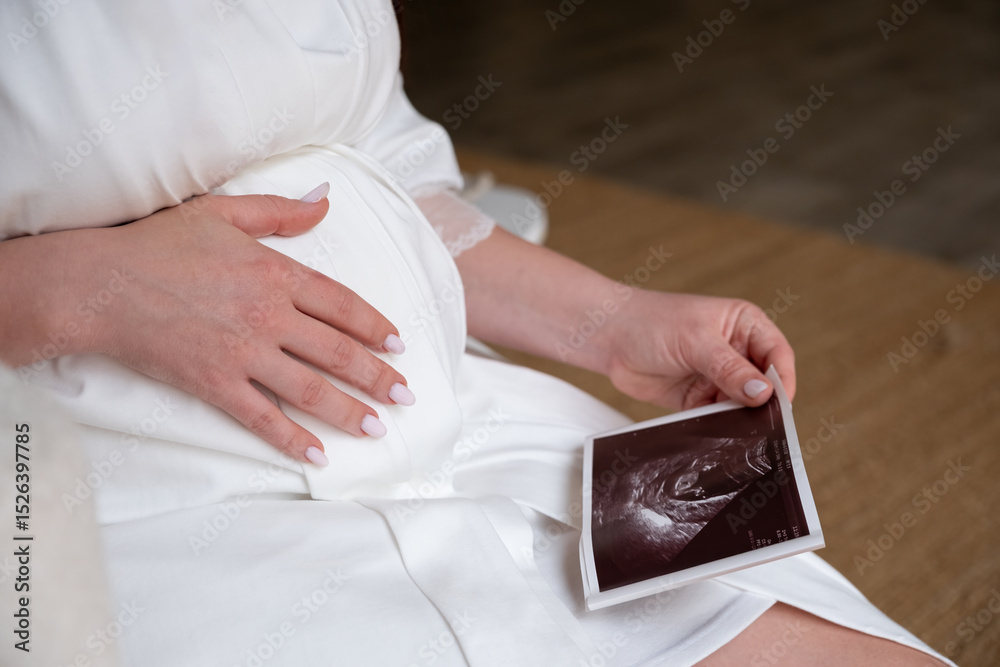 Obraz premium A pregnant woman admiring an ultrasound image of her unborn baby