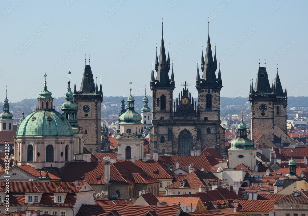 Fototapeta premium Prague cityscape featuring towers, domes, and red rooftops under a clear sky