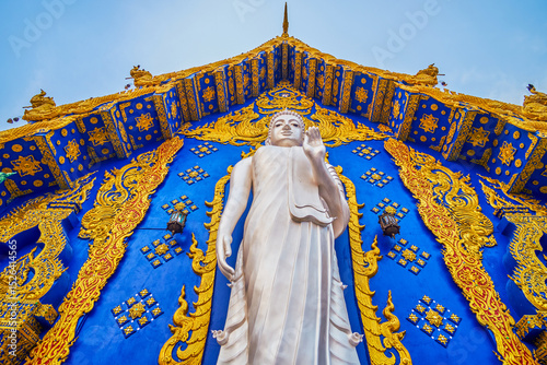 Buddha Statue and blue-golden Viharn Hall, Wat Rong Suea Ten, Chiang Rai, Thailand photo