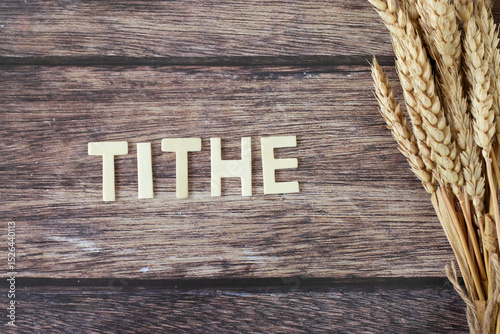 Tithe text with ripe wheat on wooden background. Top view. Generosity, Christian giving, offering, and faith in God Jesus Christ, biblical concept.