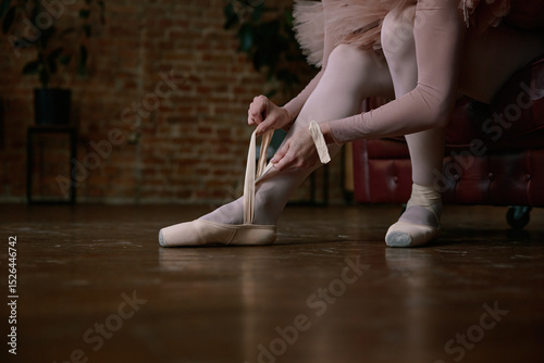 Ballerina is gently and delicately wearing her ballet shoes