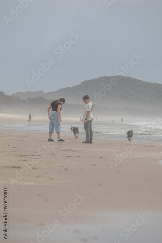 Teen boy and teen girl with dogs on a beach photo