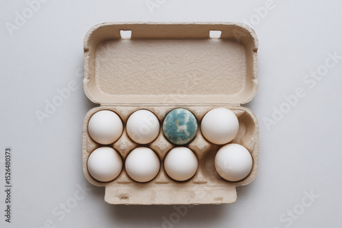 Egg recall concept. Egg carton with white eggs and one unique colored egg inside. photo