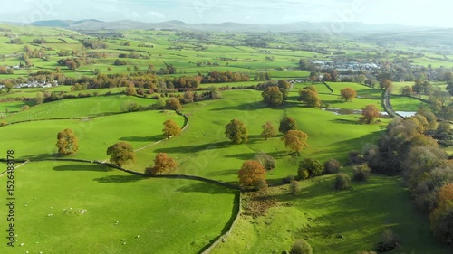 Aerial autumn view of endless lush pastures and farmlands of England. Beautiful English countryside with emerald green fields and meadows. Rural landscape on sunset. United Kingdom.