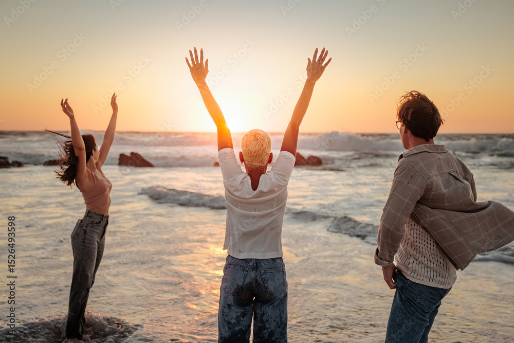 Fototapeta premium Friends raising arms enjoying golden sunset at beach