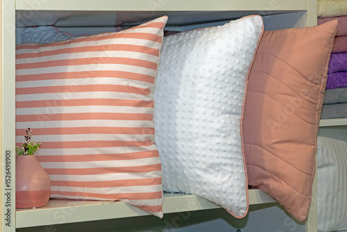 Pile of large decorative pillows on shelf in home interior