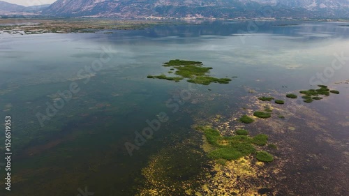 Aerial view of Isikli Lake with green vegetation and mountain reflections in Civril, Denizli