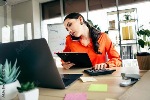 Photography Focused businesswoman multitasking in modern office, analyzing data and managing
