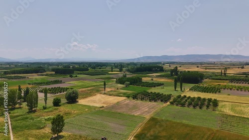 Aerial view of cultivated fields, trees and a mountain under a blue sky with clouds in Civril