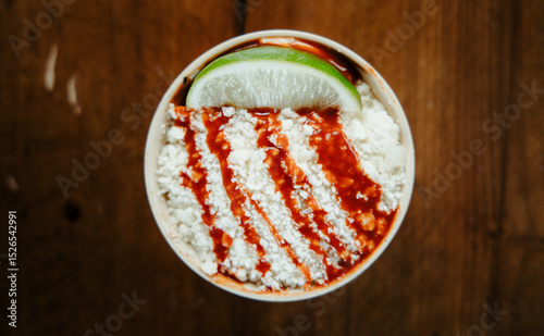 A Cup of Elote with Cheese and a Lime Wedge Shot from Above photo