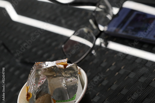 Candy wrapper in a paper cup of coffee.