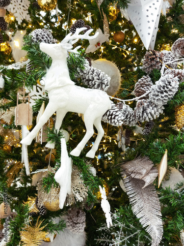 Close-up of white toy deer on a richly decorated Christmas tree.