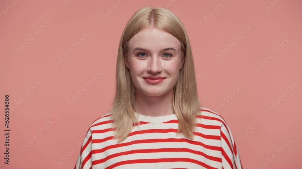 Playful young woman winking at camera on pink Playful young woman winking at camera on pink