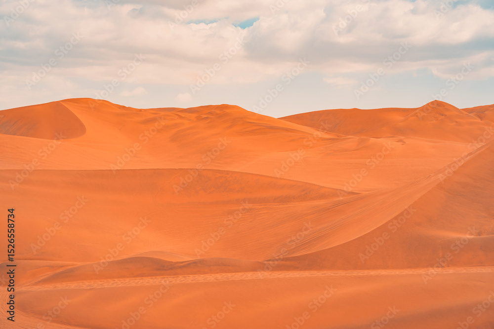 Naklejka premium Golden sand dunes of Ica desert under a clear blue sky in Huacachina, Peru