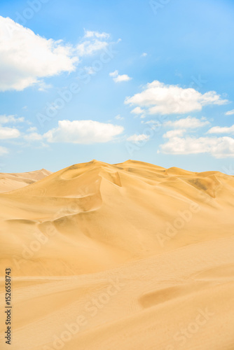 Fototapeta Naklejka Na Ścianę i Meble -  Golden sand dunes of Ica desert under a clear blue sky in Huacachina, Peru