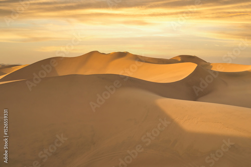 Fototapeta Naklejka Na Ścianę i Meble -  Ica desert landscape at sunset with smooth golden sand dunes near Huacachina, Peru.
