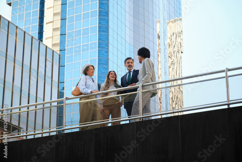 Businesspeople having a conversation on a bridge in a modern business district with skyscrapers