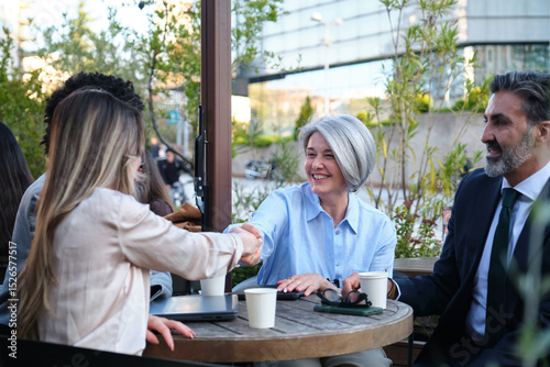 Business people shaking hands after reaching an agreement during a meeting at an outdoor cafe