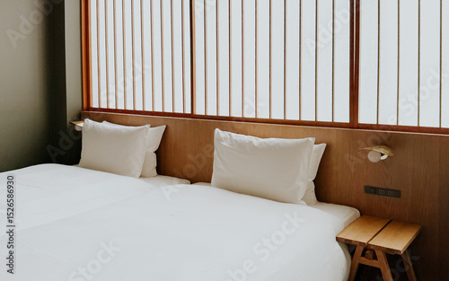 Minimalist Japanese hotel room with twin beds and soft white bedding, shoji screen. Modern ryokan interior 
