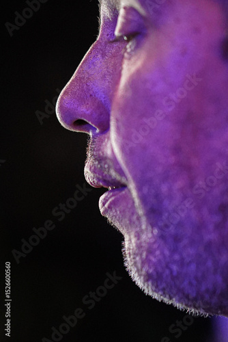 Profile of a man breathing under purple light, possibly in a night club or bar