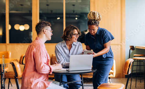 Team discussion with three adults using technology in a modern coworking space