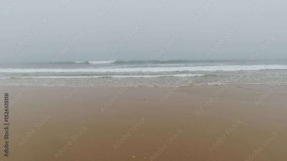 Misty Ocean Waves Rolling onto Portuguese Beach on Overcast Day Misty Ocean Waves Rolling onto Portuguese Beach on Overcast Day