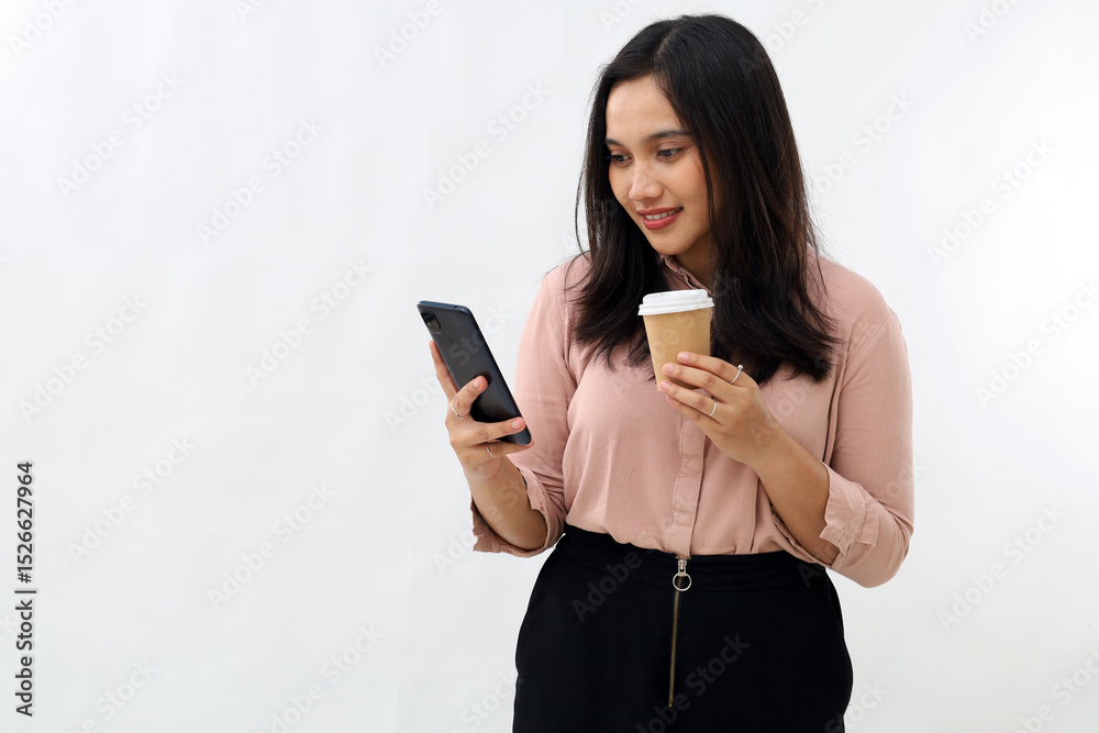 Naklejka premium Portrait of modern Asian woman looking at mobile phone, holding coffee paper cup, using smartphone app, standing on white background.