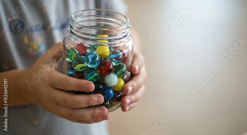 Child holding a glass jar filled with colorful glass spheres, showcasing childhood fun and games.