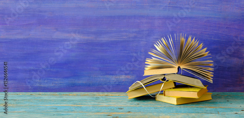 Heap of multicolored books on blue grungy background, education,knowledge is power,reading concept, free copy space.
