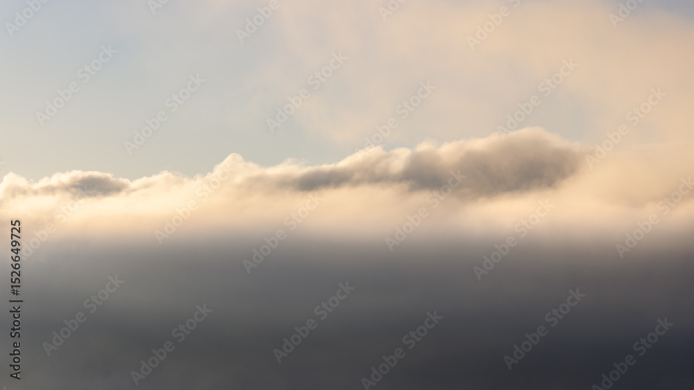 Obraz premium Layers of mist and clouds illuminated by the soft morning sunlight, creating a dreamy atmospheric scene perfect for creative backgrounds