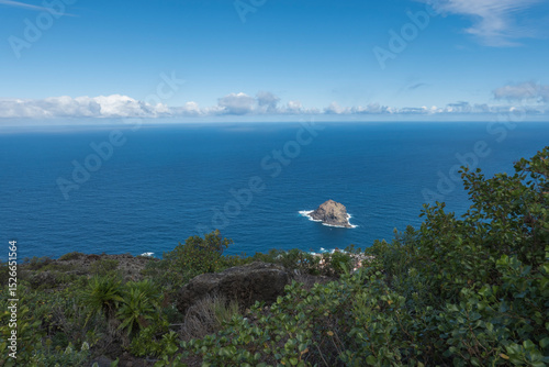 Aerial view of Roque de Garachico big rock in the ocean from Mirador de Garachico view point. Blue ocean with green vegetation. Popular tourist destination, Tenerife Canary Islands.